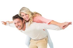 handsome man giving piggy back to his girlfriend on white background